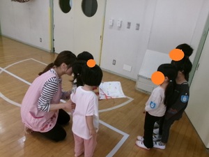 5歳児クラスが3歳児クラスに絵をプレゼントしている写真。