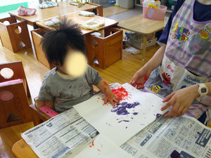 手に絵具を塗ってスタンプをしている様子