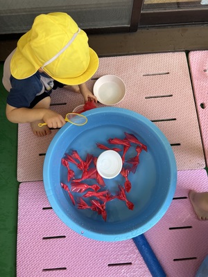 写真：金魚すくいごっこをする2歳児