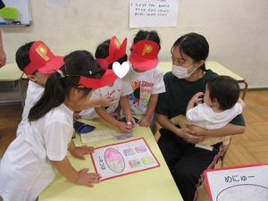 ピザ屋さん当日、小さい子にピザやメニューを渡してあげる子どもたち