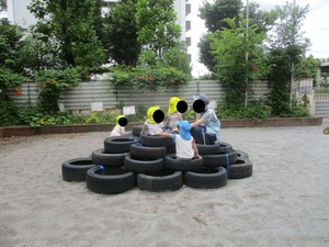 園庭にあるタイヤの築山で子どもたちが遊んでいるところ