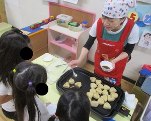 子どもたちの目の前でホットプレートに置いた焼きおにぎりに醤油を垂らしているところ