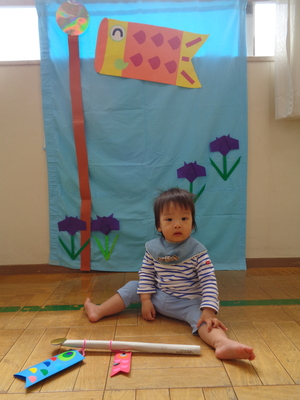 写真1　こいのぼりの背景で制作したものと写っているこども