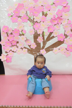 フォトコーナー　梅の花の前で写真を撮る乳児