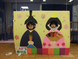 かわいいお雛さまとお内裏様お雛さまとお内裏様の顔出しパネルから子どもの顔がでている写真