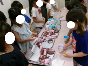 5歳児が自分たちで作ったドーナツとジュースを売っている写真