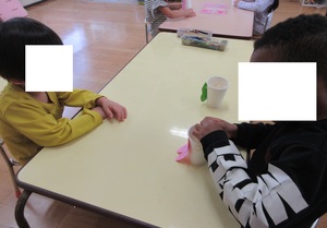5歳児クラスの子が4歳児クラスの子の手伝いをしている様子
