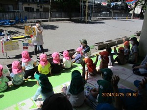 写真：ベランダで保育士の話を聞く子どもたち