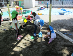 写真:砂場で穴を掘ろうとする4,5歳児の子どもたち