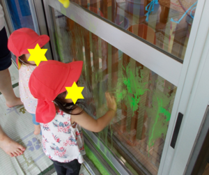 写真：窓ガラスに手で絵の具をつける子ども