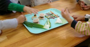 写真：1歳児クラスで野菜の切れ端を見ている様子