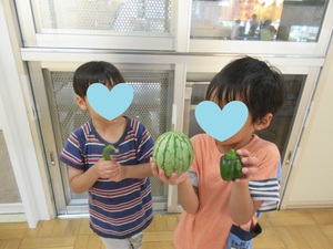 収穫した野菜を手に持つ子どもの写真