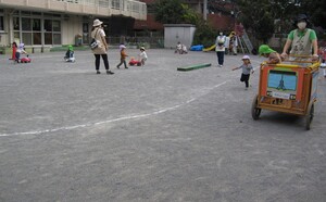 道路や踏切がある園庭で遊ぶ子どもたちの写真