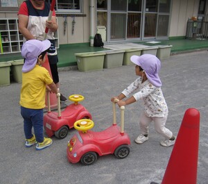 コンビカー(手押し車)を道路に見立てたコースで押している子どもの写真