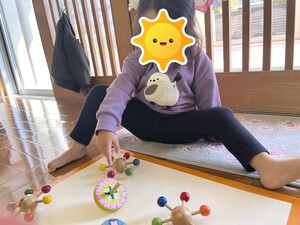 乳児が手でコマを回す様子