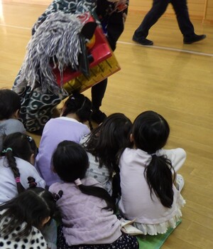 獅子に頭を噛んでもらっている子どもの姿です
