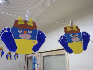 0歳児クラスが作った鬼の写真。画用紙で作った鬼に、子どもたちの足形で作った足が付けられている。