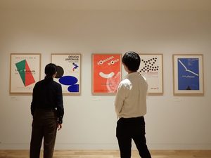 写真：小さなデザイン 駒形克己展　壁に掛けられた作品を見る来館者